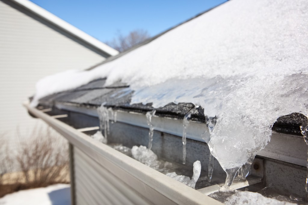 Frozen gutter filled with ice caused by repeated snowmelt and refreezing
