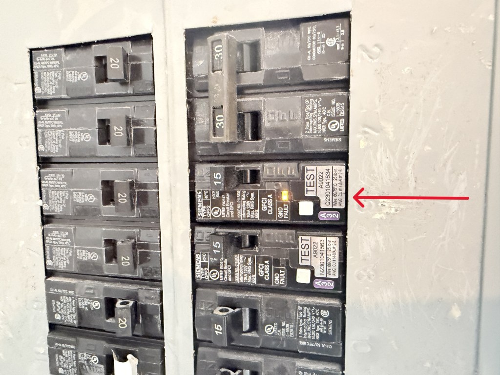 GFCI circuit breaker inside electrical panel with illuminated ground fault indicator light